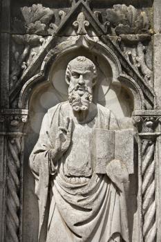 Royalty Free Photo of a Relief Sculpture of a Bearded Male Figure Standing With a Book and Holding up Two Fingers