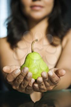 Royalty Free Photo of a Woman Holding a Pear Outstretched