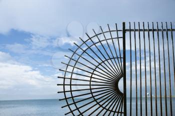 Royalty Free Photo of a Decorative Wrought Iron Fence at the Edge of the Sea