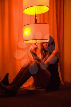 Royalty Free Photo of a Woman Sitting on the Floor Holding a Lamp