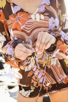 Royalty Free Photo of a Close-up of a Woman's Hands Tying the Front of a Floral Dress
