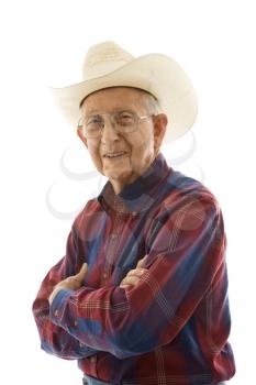 Portrait of smiling Caucasion elderly man wearing plaid shirt and cowboy hat with arms crossed.