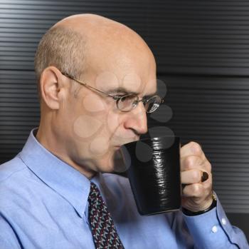 Caucasian middle-aged businessman drinking from coffee cup.