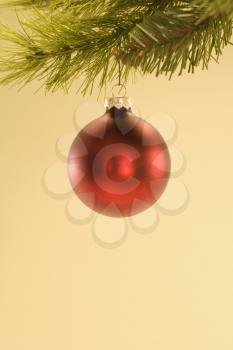 Royalty Free Photo of a Round Red Christmas Ornament Hanging From a Pine Branch