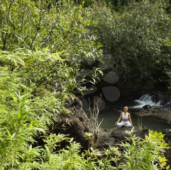 Royalty Free Photo of a Woman Sitting on a Boulder by a Creek Meditating in Maui, Hawaii