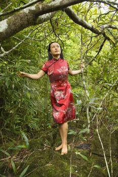 Royalty Free Photo of a Woman in Ethnic Attire Standing on a Rock in Bamboo in Maui, Hawaii