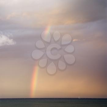 Rainbow spreading across sky on coast in Maui Hawaii.