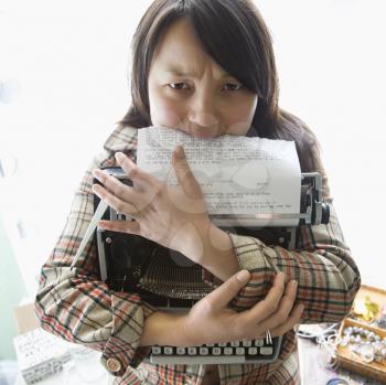 Royalty Free Photo of a Woman Holding a Typewriter and Biting a Page