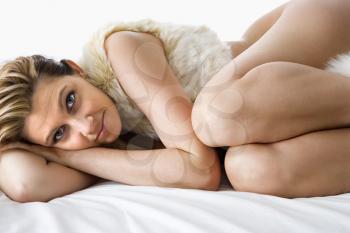 Royalty Free Photo of a Woman Lying Curled Up on a Bed