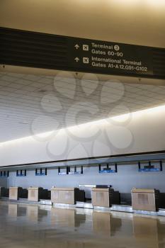 Royalty Free Photo of Signs for Terminal and Gates With an Empty Check-in Station at an Airport