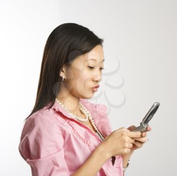 Royalty Free Photo of an Asian Woman Smiling and Text Messaging on a Cellphone