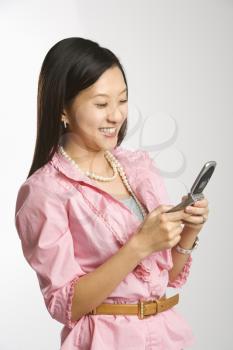 Royalty Free Photo of a Female Smiling and Text Messaging on a Cellphone