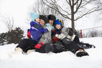 Royalty Free Photo of a Family of Four Sitting in the Snow Smiling