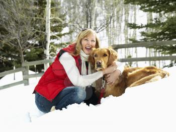 Royalty Free Photo of a Woman hugging dog and smiling in snow covered Colorado landscape