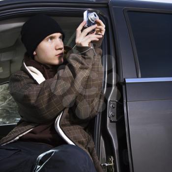 Royalty Free Photo of a Teenage Boy Taking a Picture From His Car
