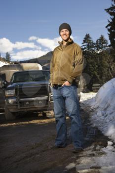 Royalty Free Photo of a Man Standing in Front of a Truck With his Hands in His Pockets Smiling