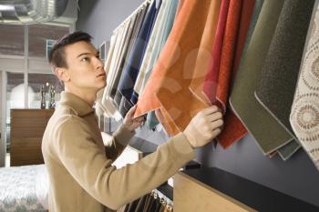 Royalty Free Photo of an Asian Male Looking at Fabric Swatches in a Retail Store