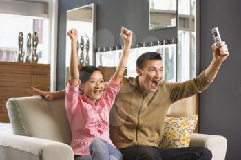 Royalty Free Photo of an Asian Couple Cheering While Watching Television