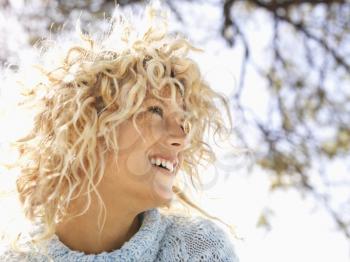 Head and shoulder portrait of attractive young woman with curly blond hair smiling in Maui, Hawaii.