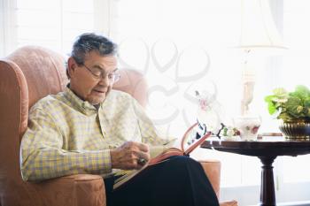 Mature Caucasian man sitting in chair reading a book.