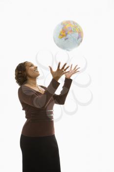 Woman throwing world globe into air and smiling.