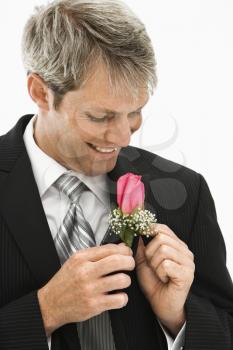 Caucasian groom adjusting boutonniere.