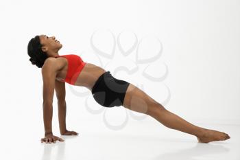 Profile of African American young adult woman exercising in strength training position.