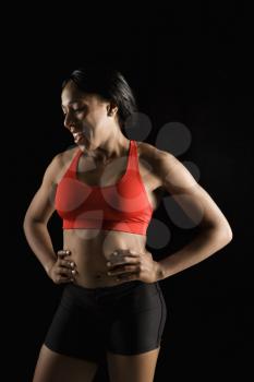 Smiling African American young adult woman in athletic apparel with hands on hips.