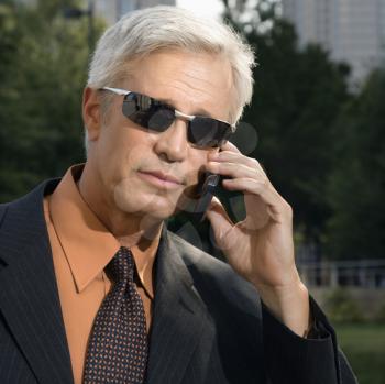 Royalty Free Photo of a Middle-aged Businessman in Sunglasses Talking Outdoors on a Cellphone