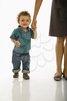 Royalty Free Photo of a Toddler Boy Holding onto His Mothers Hand Smiling