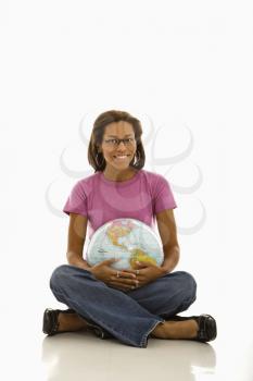 African American woman sitting on floor holding globe and smiling at viewer.