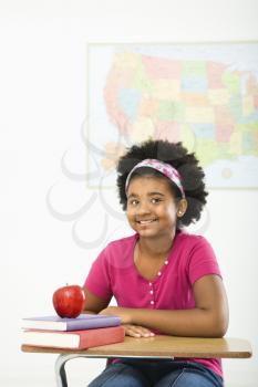 African American girl sitting in school desk smiling at viewer.