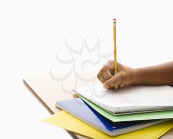 Royalty Free Photo of the Hand of a girl at school desk writing in notebook with pencil