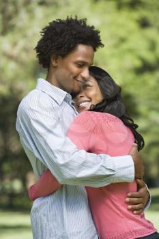 Attractive couple smiling and embracing in park.