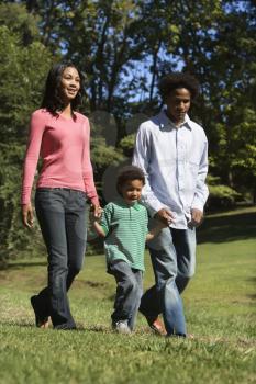 Royalty Free Photo of Parents and Young Son Walking in a Park Holding hands