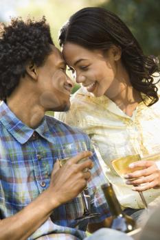 Couple getting close having wine on romantic park picnic.