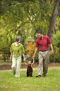 Royalty Free Photo of a Mother and Father Holding Their Toddlers Hands in a Park