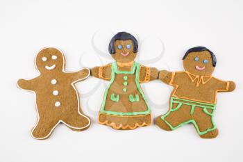 Three male and female gingerbread cookies holding hands.