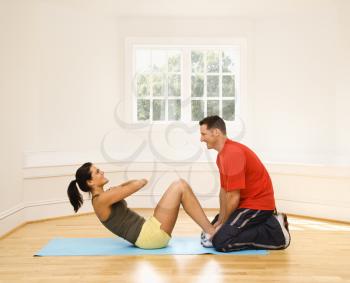 Man holding woman's feet down as she does sit up exercises.