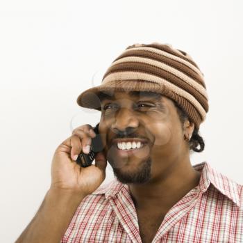 African-American mid-adult man wearing hat and smiling while talking on cell phone.