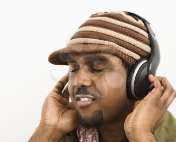 African-American mid-adult man wearing knit hat and listening to headphones with eyes closed.