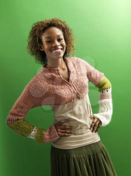 Royalty Free Photo of a Pretty Woman Standing Against a Green Background with Hands on Hips Smiling