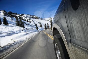 Perspective shot of SUV driving down road in snowy Colorado during winter.