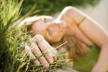 Selective focus portrait of young woman relaxing in grass.