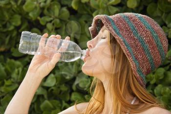 Royalty Free Photo of a Woman Wearing a Hat and Drinking Water