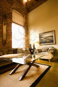 Interior of living room with large window, brick wall, coffee table, and sofa.