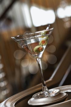 Martini glass sitting on the bottom of a banister railing. Vertical shot.