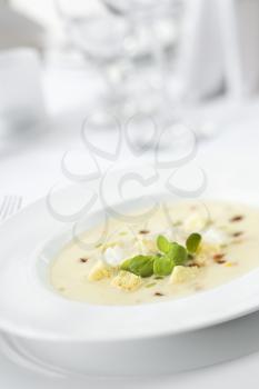 Bowl of gourmet soup elegantly displayed with garnish in a restaurant. Vertical shot.