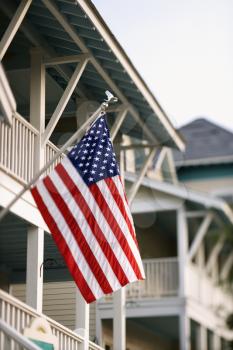 An American flag hanging from a flagpole on the front of a home. Vertical shot.