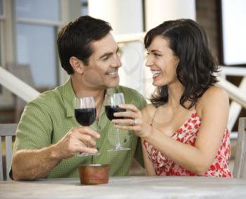 Man and woman toast with red wine glasses at an outdoor cafe. Horizontal shot.
